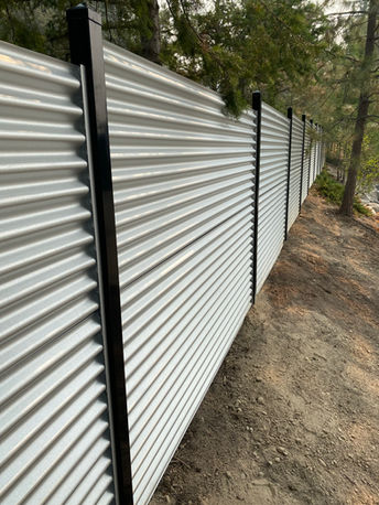 corrugated galvanized fencing with black metal posts installed by blue rhino fence in vernon bc