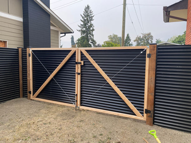 black corrugated tin fence gate with wooden posts shows the beauty and functionality of this type of fencing in vernon bc