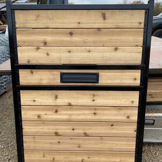 a custom built gate with 2.5" square black metal posts and treated cedar planks