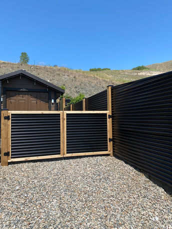 corrugated metal and wood fence with two tiers, tall for the perimeter of this vernon bc home and short for the gate to the back yard