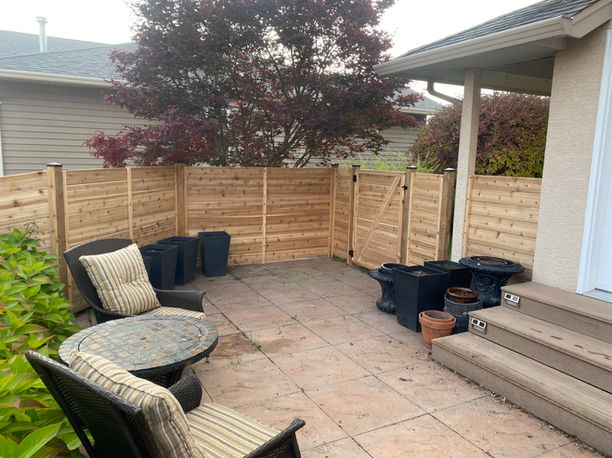 custom built cedar wood fence surrounding a backyard with tiles and patio furniture in kelowna bc