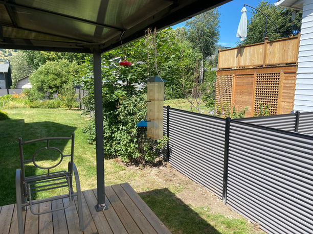 galvanized metal corrugated fence panels attached to black steel powder coated posts surround a residence in the North Okanagan
