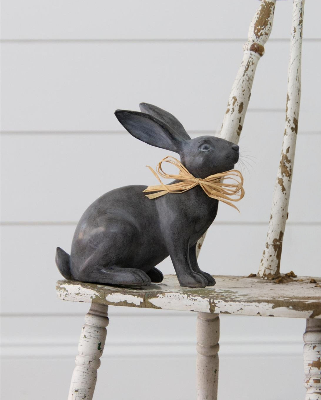 8.5" H x 8" W x 4" D polyresin & stone powder rabbit with charcoal finish & raffia bow around neck
