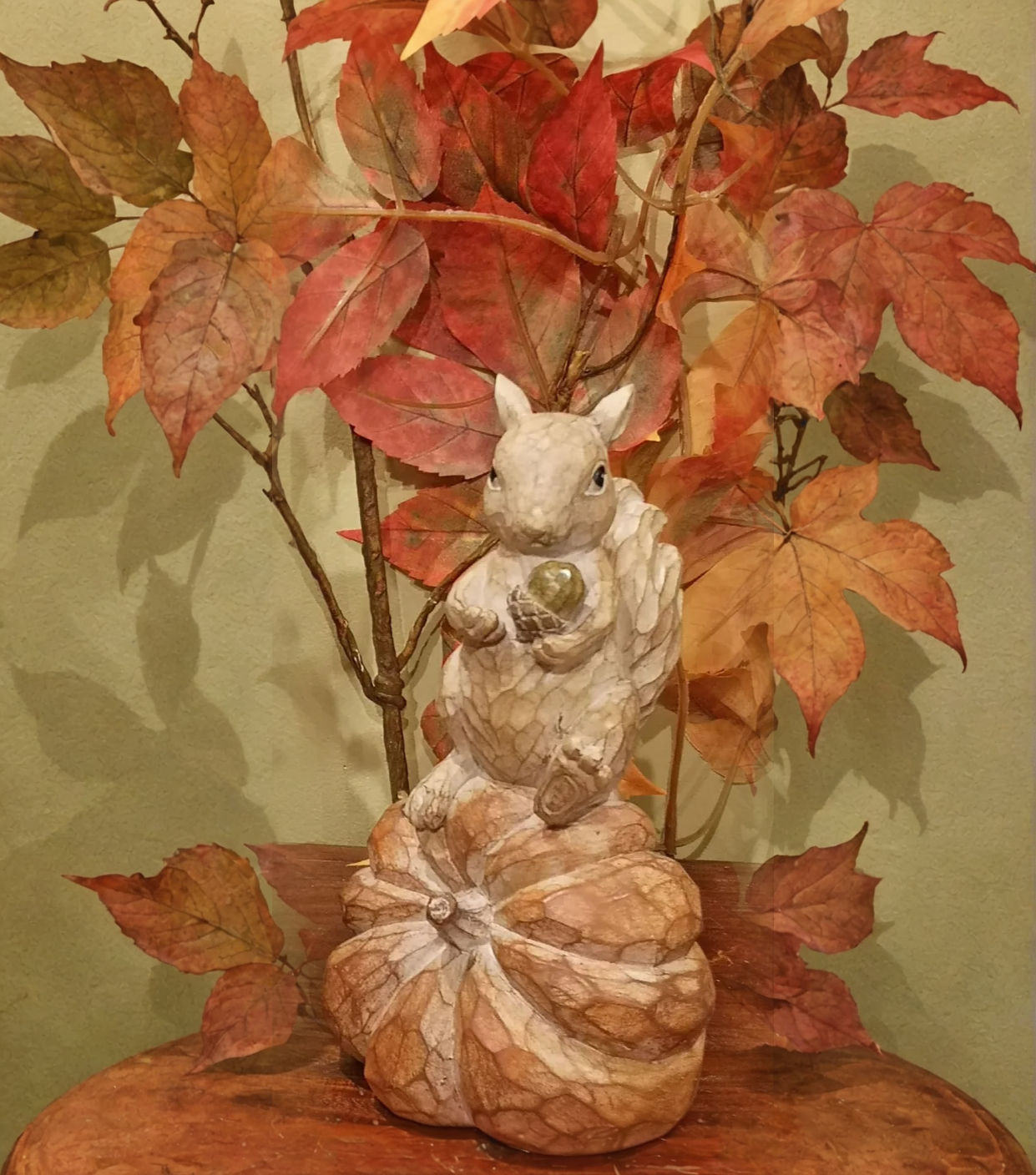 8" resin squirrel holding an acorn while sitting on a pumpkin, looks like carved wood, fall decor