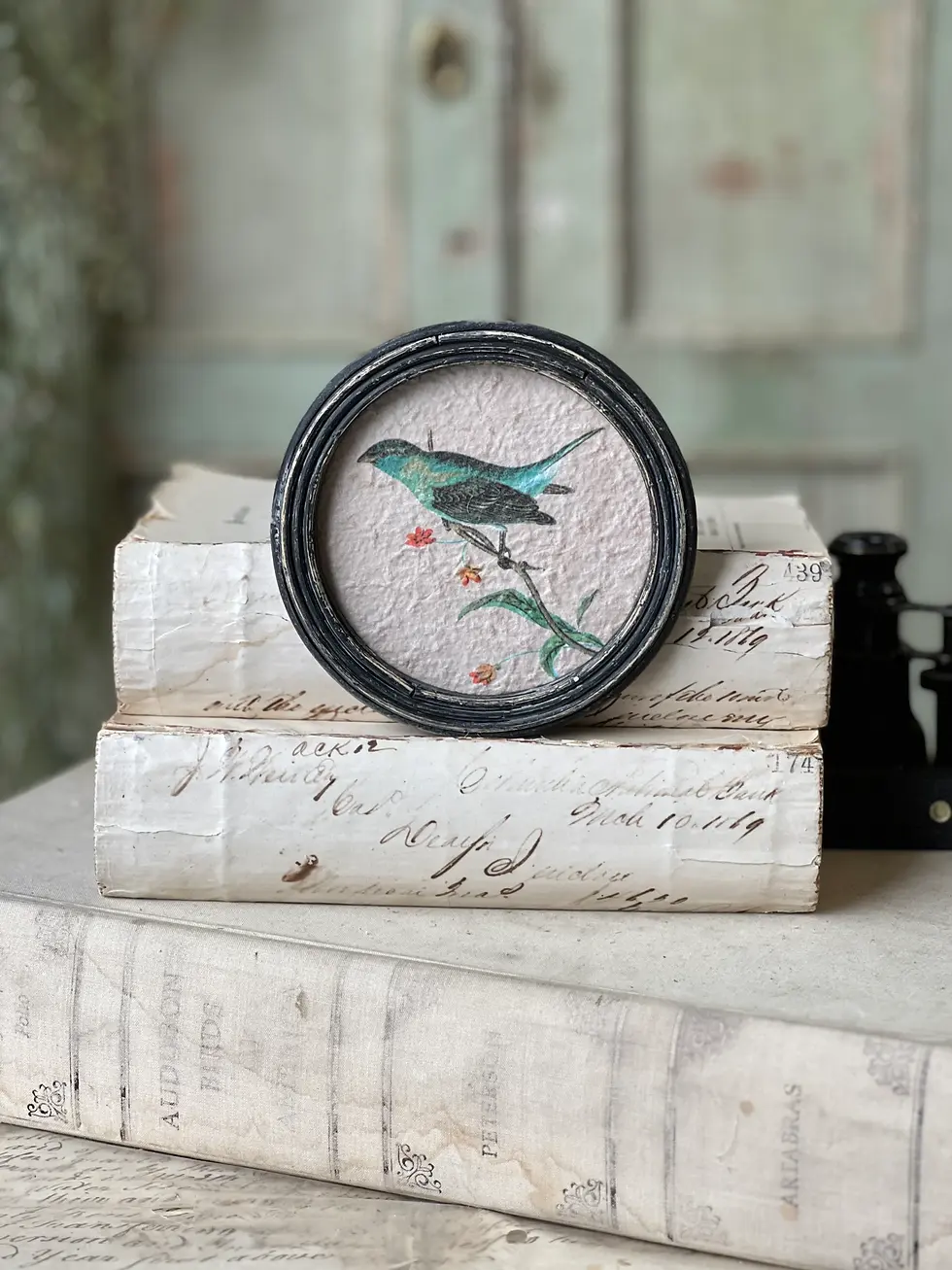 5" x 5" textured paper printed with a blue bird on a branch, black wooden round frame, sawtooth hanger