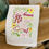 Thumbnail: White cotton tea towel embroider with the verse "we love because He first loved us" John 4:19