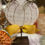 Thumbnail: 3.25” X 2.25” X 9“ flat white wood pumpkin with 2 metal leaves,  on a metal rod with wood base to allow free standing