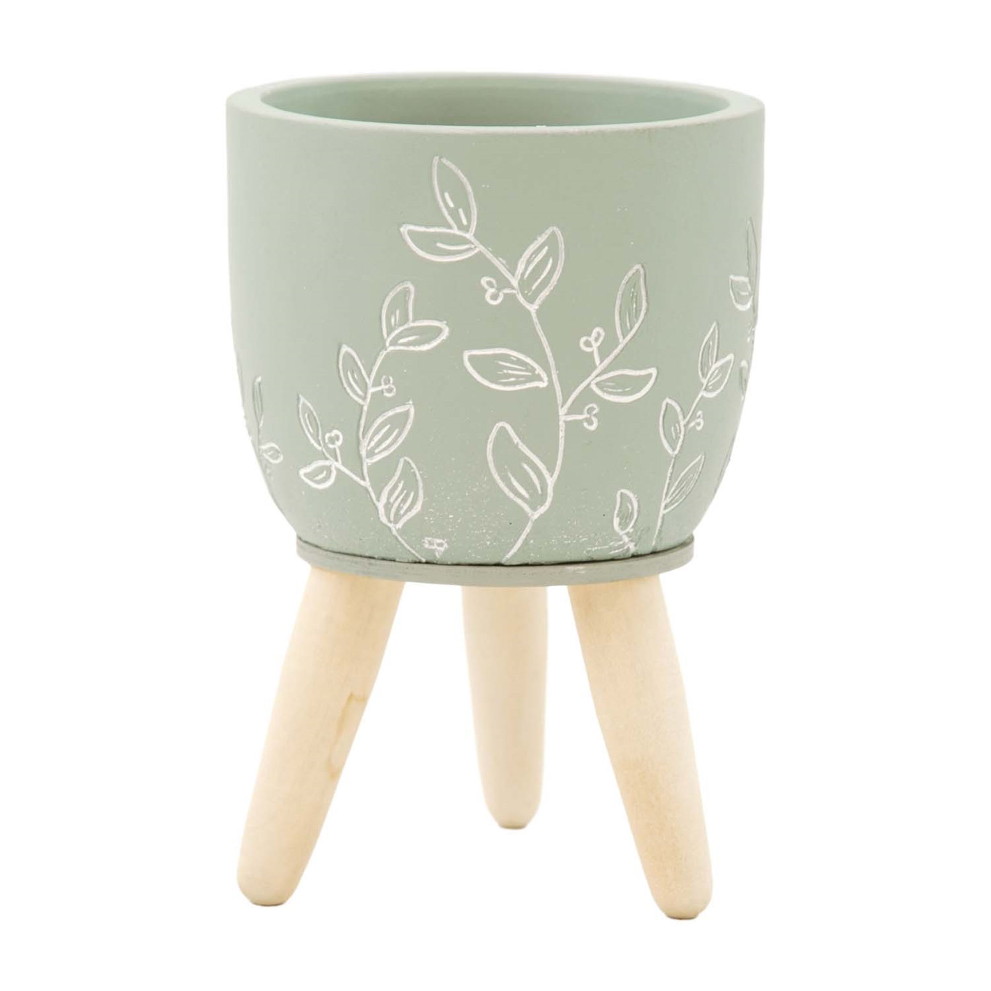 4" x 6.25" small resin pot, pot is green with carved foliage details in white, pot is on 3 natural wood legs