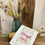 Thumbnail: white cotton tea towel embroidered with verse "she is clothed with strength  & dignity" Proverbs 31:25