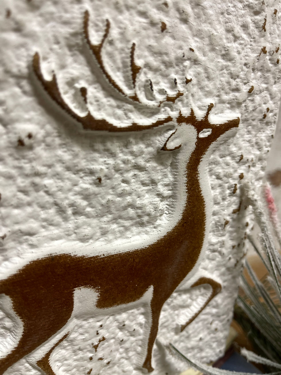 Close up of Wood block with textured white finish and a raised image of a brown reindeer.
