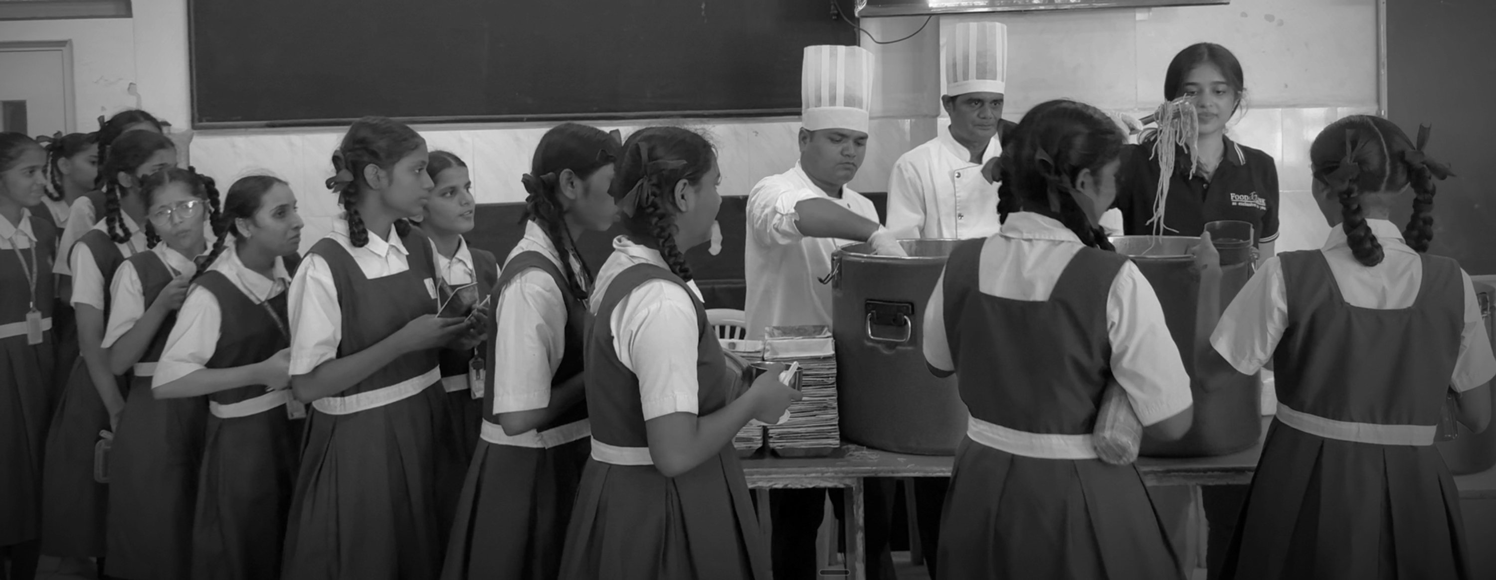 Foodlink chefs and Ayanna serving a meal to schoolgirls