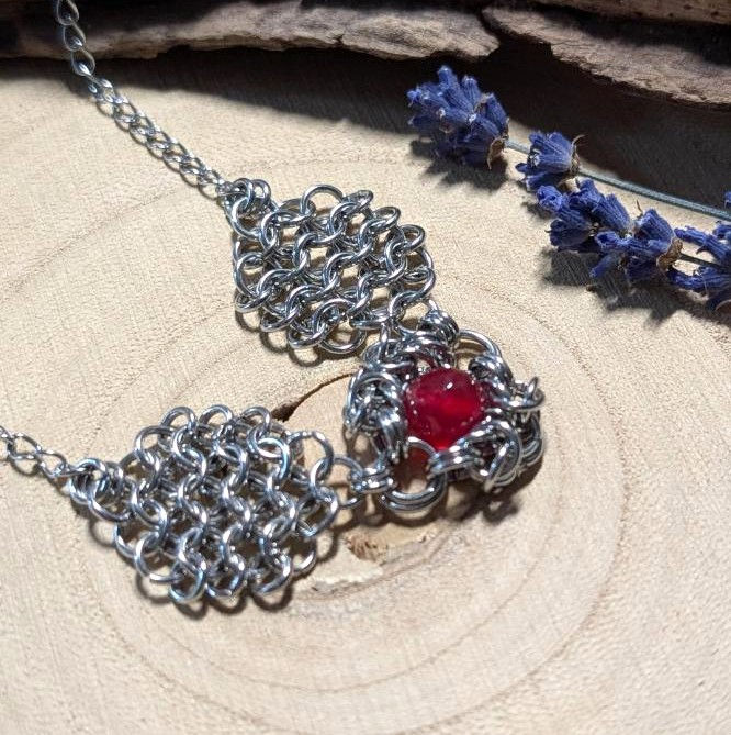 Miniatura: Detal bransoletki z naturalnego chalcedonu i hematytu, koraliki w ciepłej czerwieni i metalicznej szarości.