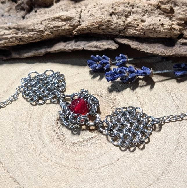 Miniatura: Bransoletka z czerwonego chalcedonu i hematytu ułożona na drewnianym tle.