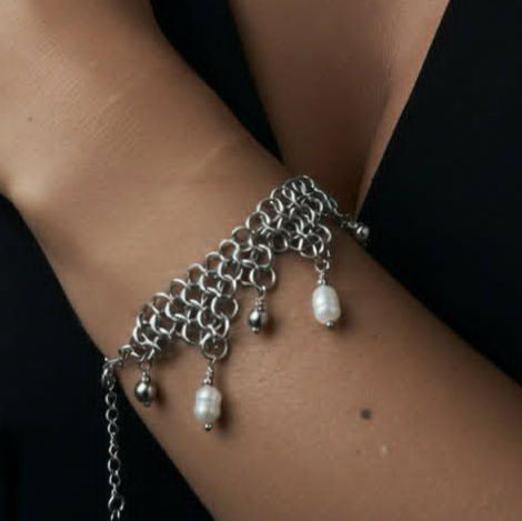 Zbliżenie na nadgarstek modelki z bransoletką chainmail z pereł słodkowodnych.