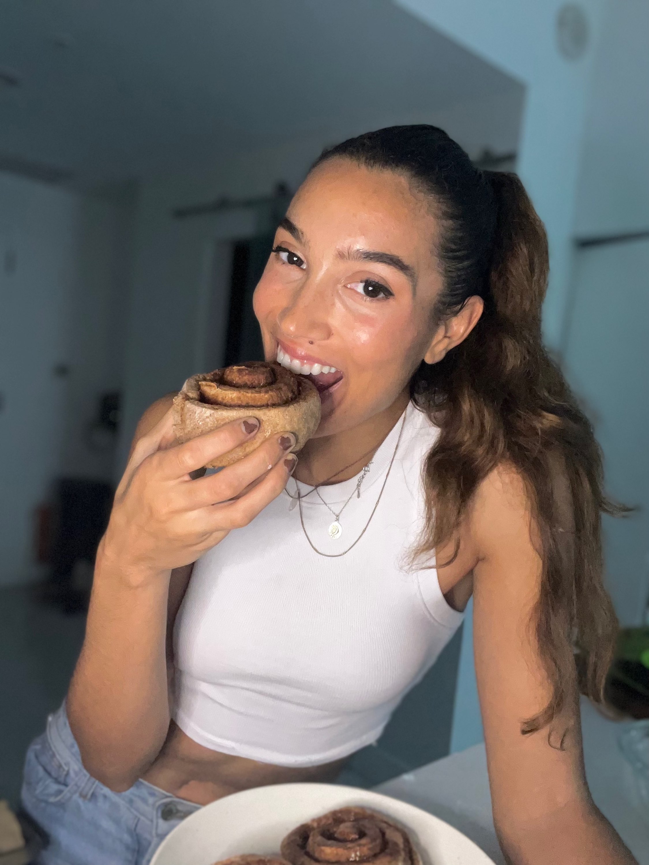 girl eating a homemade cinnamon roll in her kitchen during the holidays
