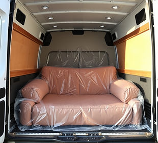 Sofa in clear protective wrapping in the back of a large white transit van.jpg