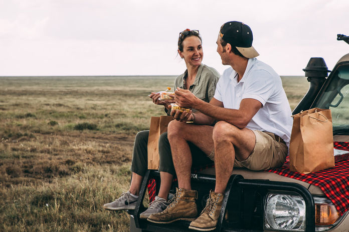 A couple enjoying a private picnic lunch on the open savannah during a Serengeti honeymoon safari