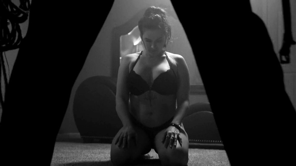 A cinematic image of a submissive woman in lingerie in an erotic videography session