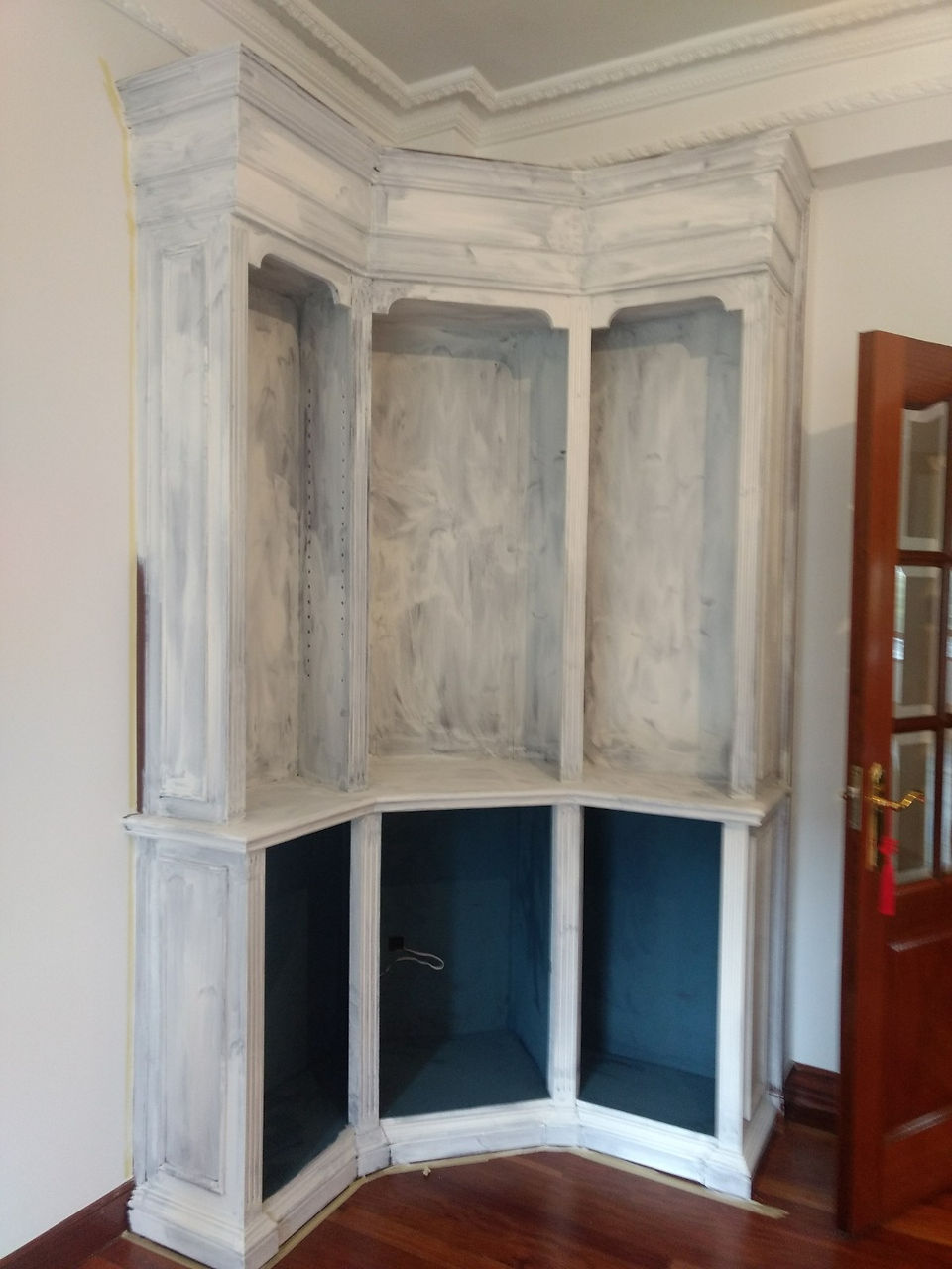 La segunda zona de la que os hemos hablado es la estantería. Una pieza con altura y con presencia dentro del espacio. Siguiendo con los mismos tonos del resto de los muebles pero con un punto diferente en las baldas, aplicando un veteado sutil con Coco y para darle un punto de madera lavada acabado con Wax White de Annie Sloan - TRATE Tienda Taller