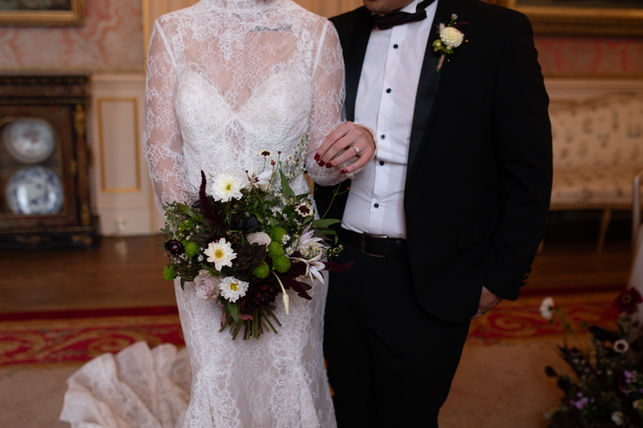 A shot of a bride and groom's outfits and bridal bouquet