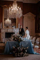 A bride and grrom walk around the reception table of their wedding