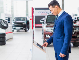 Man checking tire shop inventory on computer with tires behind him.