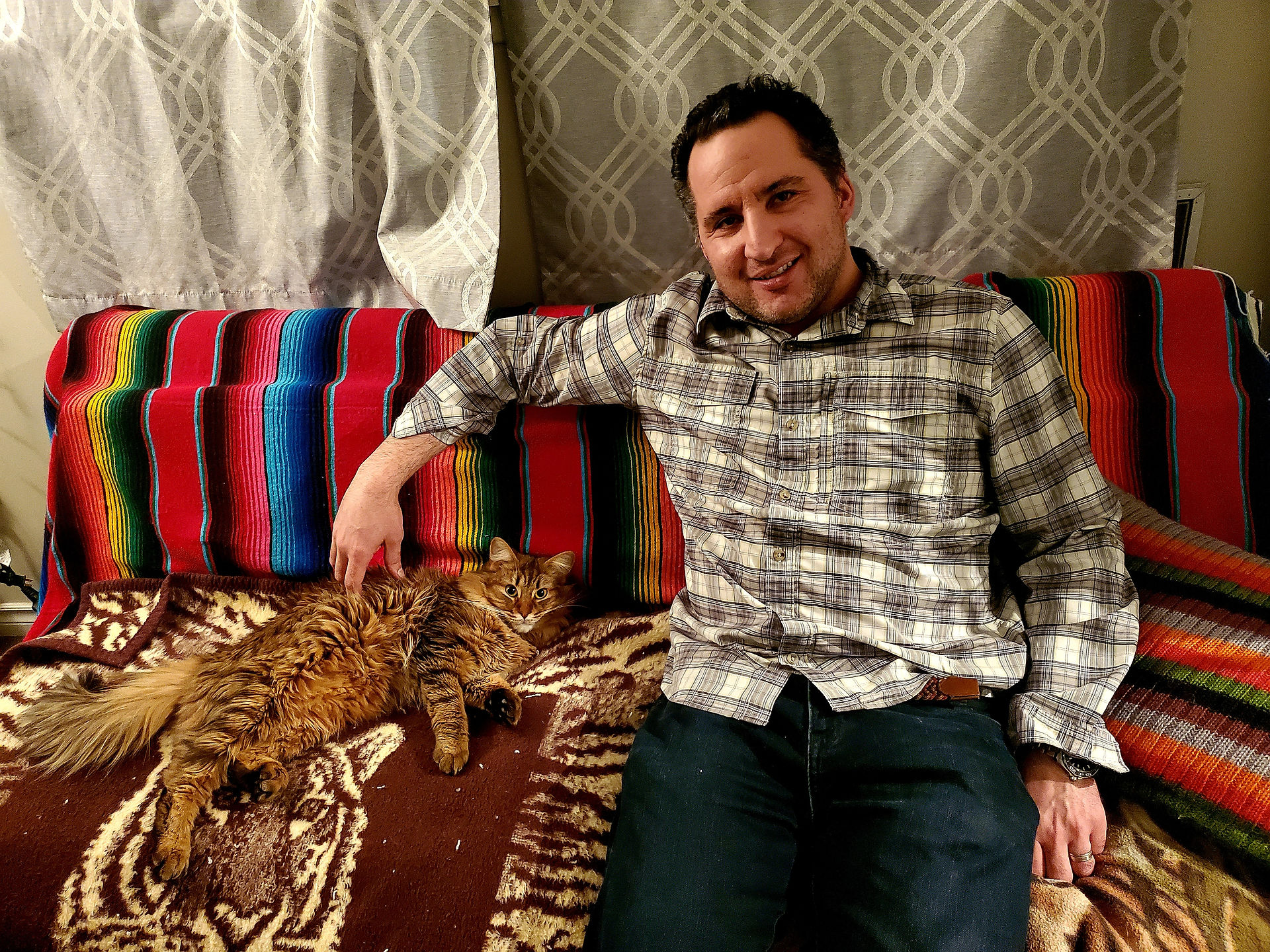 Pavel the cat with his favorite cat sitter.  They are sitting on a bed with the sitter providing pets.