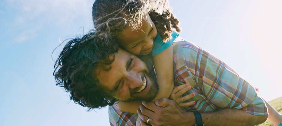 Happy Father Carrying Laughing Child Outdoors on His Back