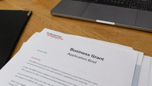 Enterprise Singapore business grant application brief on a desk, illustrating MRA grant planning and eligibility review for overseas expansion.
