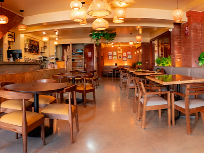 Restaurante con mesas y sillas de madera; ambiente cálido, iluminación tenue.