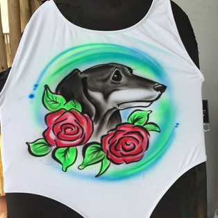 A portrait of a dog surrounded by roses airbrushed painted onto a white swimsuit.