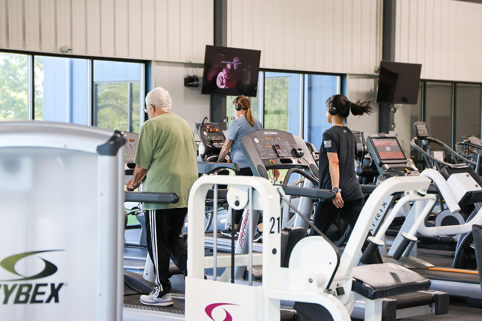 Three people exercising on treadmills and using CYBEX gym equipment.