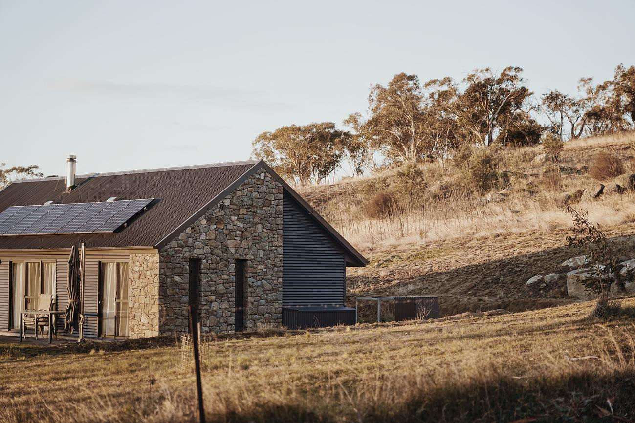 A cottage at Touchdown is pictured at sunset, nestled amongst the bush, offering a peaceful escape.