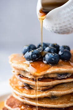 Maple syrup pouring on stack of pancakes