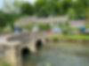 Stone bridge over the River Coln in Bibury village, with views towards The Swan Hotel — a classic Cotswold destination known for its riverside charm and historic architecture.