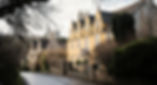 Castle Combe, one of the prettiest villages in the Cotswolds, with honey-coloured stone cottages lining a peaceful, winding street. The ancient stone bridge crosses the tranquil river, surrounded by lush greenery and historic charm. A must-visit destination for visitors exploring the English countryside and traditional Cotswold villages.