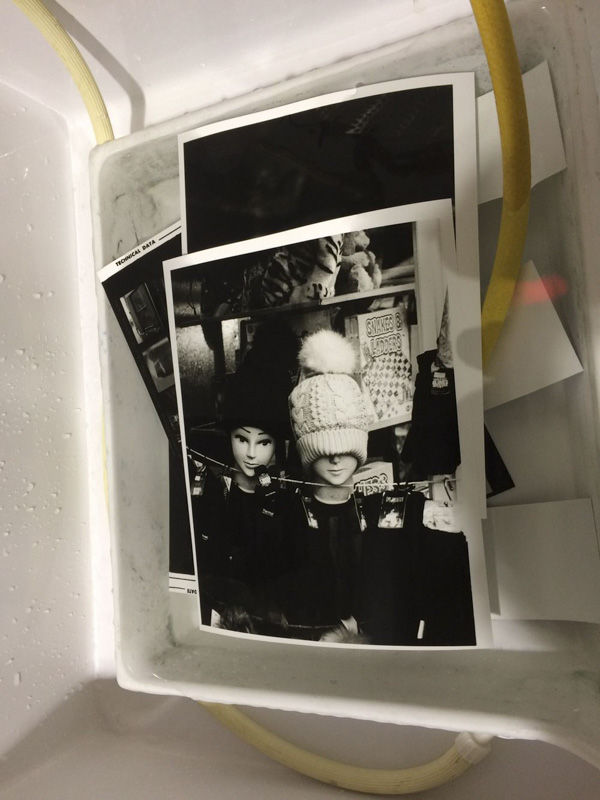 Black and white film photograph of two mannequin heads in hats being developed