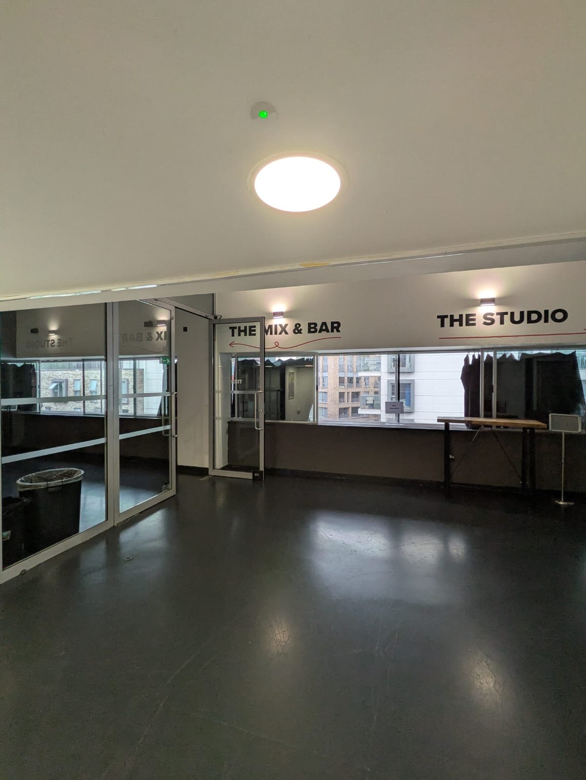 The entrance to level four from the lifts. A wide open space with windows on one wall. Signs point to “The Mix & Bar” and “The Studio”.
