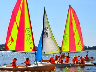 dzieci pływają na łódkach na jeziorze podczas kolonii żeglarskich na Mazurach