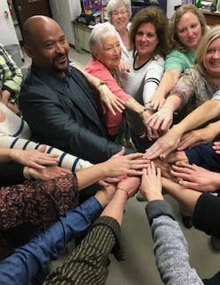 People standing with hands put together in a circle