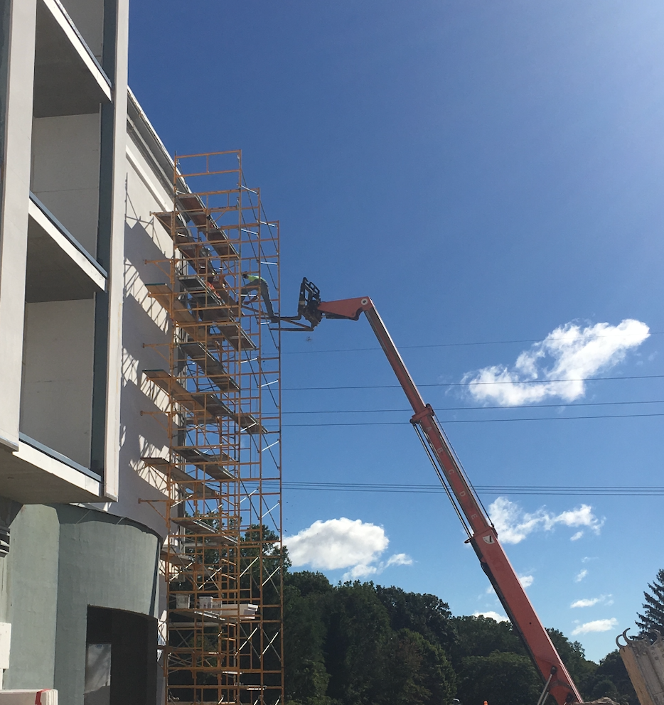 Construction workers performing elevated work from frame scaffolding on a commercial building