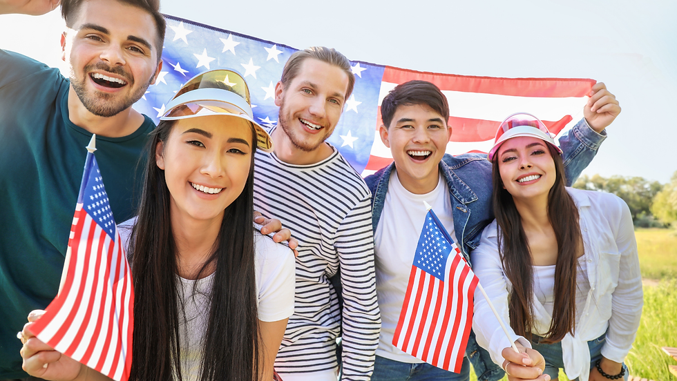 A diverse group of smiling young adults holding American flags with a U.S. flag in the background, symbolizing the opportunities and welcoming environment of the U.S. market for entrepreneurs.