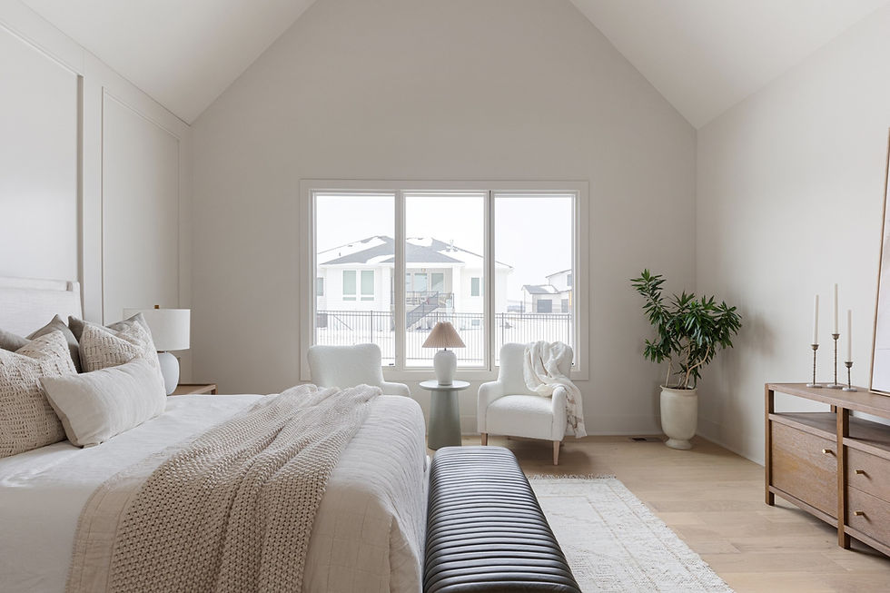 A bright, modern bedroom with vaulted ceilings, neutral décor, and large windows overlooking a snowy neighborhood, showcasing the refined craftsmanship and design style of home builders Omaha.