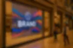 A luxury storefront resembling Marina Bay Sands retail interiors, featuring transparent LED film with subtle animated visuals displayed on the glass while shoppers pass by in a high-end mall setting.
