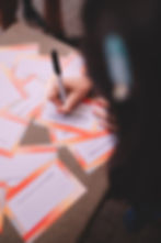 Pessoa escrevendo em cartões de identificação em evento.