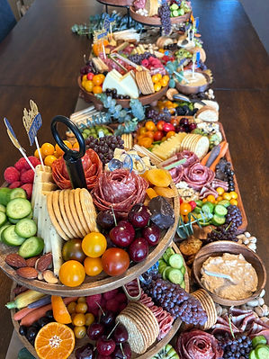 A full view of a grazing table featuring meats, cheeses, fruits, crackers