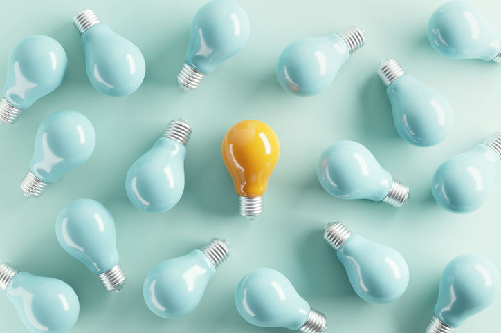 yellow lightbulb surrounded by blue light bulbs
