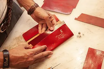 italian artisan is making a red leather wallet in his leather store florencia.webp