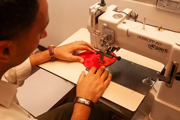 owner of the leather store in florence sewing a leather handbag.webp
