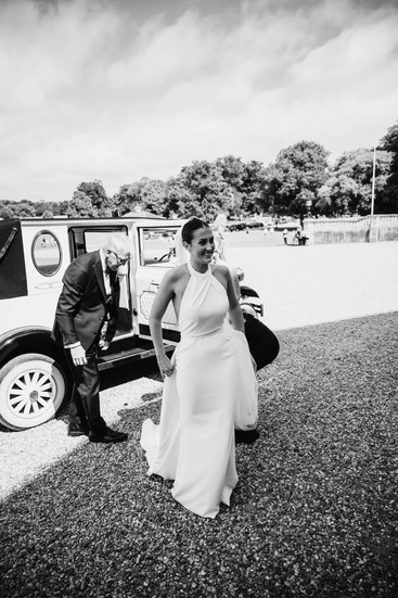 Bride getting out of her car with Dad holding her dress